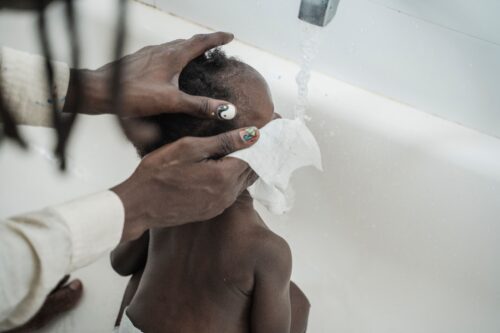 A tender moment of a child being washed during bath time with care and attention.