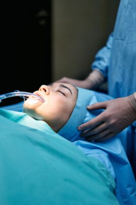 Close-up of a patient under anesthesia in an operating room, surrounded by medical professionals.